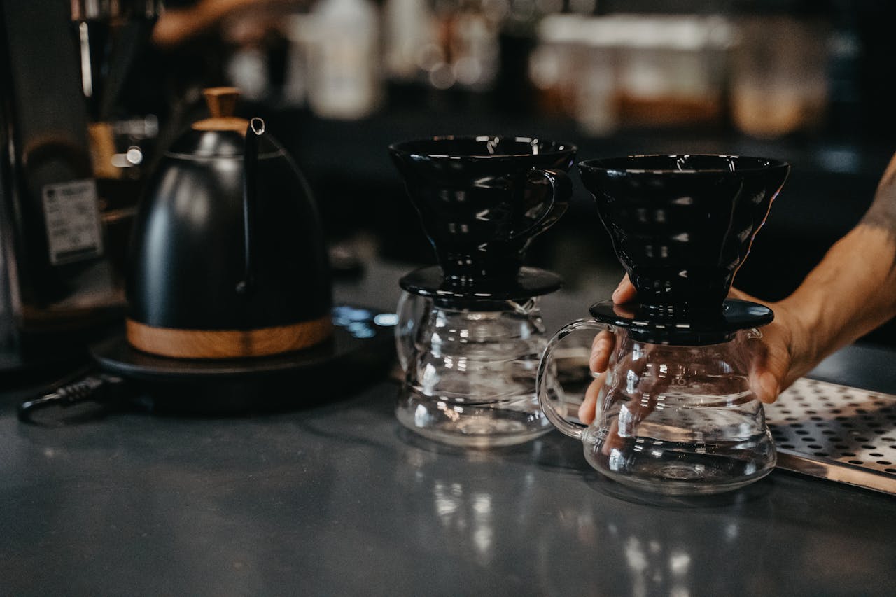 Professional barista setting up drip coffee makers in a stylish café setting, highlighting artisanal coffee preparation.